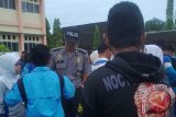 Salah seorang aparat kepolisian melakukan pemeriksaan tas siswa SMA Negeri 1 Kabupaten Penajam Paser Utara (PPU) sesaat sebelum pengumuman Ujian Nasional (UN). (Bagus Purwa/ANTARA Kaltim)

