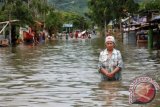 Warga melintas di genangan air ketika banjir melanda pemukiman di jalan Diponegoro, Limba U, Kota Gorontalo, Rabu (15/5). Banjir akibat meluapnya Sungai Bulango semakin meluas akibat hujan lebat terus terjadi. ANTARA FOTO/Adiwinata Solihin/ed/Spt/13