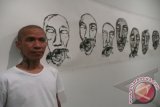 Pelukis S. Teddy, 43, kelahiran Padang, Sumatra Barat, bergaya di latar belakang lukisan "Wajah-Wajah" karyanya, pada acara pembukaan pamerannya bertajuk "Jalan Gambar", di Galeri Salihara, Jakarta, Sabtu malam (1/6). Pameran seni gambar ini akan berlangsung hingga 30 Juni 2013. ANTARA FOTO/Dodo Karundeng/ed/pd/13.