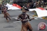 Sejumlah seniman Papua sambil membawa bendera merah putih menyajikan tari kreasi dalam parade Pesta Kesenian Bali ke-35 di Denpasar, Bali, Sabtu (15/6). Kegiatan tahunan bidang seni budaya itu berlangsung 15 Juni-13 Juli 2013 dengan melibatkan sekitar 15 ribu seniman dari Bali, grup kesenian dari beberapa daerah di tanah air dan 3 grup kesenian dari mancanegara. ANTARA FOTO/Nyoman Budhiana
