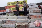 Kapolres Lampung Selatan AKBP Bayu Aji (kiri) menunjukkan barang bukti tumpukan paket ganja selundupan, di Mapolres Lampung Selatan, Rabu (3/7). Ganja seberat 4,75 ton itu diselundupkan dari Kota Pekan Baru ke Jakarta dengan truk namun berhasil digagalkan di Pelabuhan Bakauheni bersama dua orang tersangka sebagai kurir. FOTO ANTARA/Khairullah-cris/nym/2013.