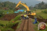 Pekerja menggunakan alat berat memadatkan kembali tanah longsor di perlintasan rel kereta api, di KM 252 Kabupaten Tasikmalaya, Jabar, Kamis (25/7). Akibat kejadian tersebut perlintasan kereta api lumpuh total. ANTARA FOTO/Adeng Bustomi/nym/2013.