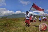 Siswa SD berjalan membawa bendera untuk mengikuti upacara di sekolah mereka yang berjarak sekitar 10-15 kilometer di Desa Looluna, Belu, NTT, Kamis (4/7). Pendidikan Dasar di perbatasan Indonesia-Timor Leste tersebut terkendala jarak dan minimnya fasilitas pendidikan, termasuk guru dan buku pelajaran sehingga masyarakat berharap pemerintah pusat dapat memberikan bantuan itu. ANTARA FOTO/Yudhi Mahatma/Koz/Spt/13