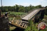 Seorang warga melihat jembatan yang putus di Desa Kedungdowo, Kecamatan Kota Nganjuk, Jawa Timur, Rabu (28/8). Jembatan penghubung jalur alternatif Nganjuk ke Kabupaten Bojonegoro tersebut putus akibat tiang penyangga jembatan patah karena abrasi arus Sungai Widas. ANTARA FOTO/Rudi Mulya/nym/2013.