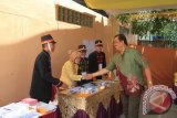 Petugas KPPS di TPS 38, Kelurahan Loa Ipuh, Tenggarong, Kukar, yang berpakain khas prajurit Kesultanan Kutai Kartanegara Ing Martadipura, saat disalami Wakil Bupati Kukar HM Ghufron Yusuf, Selasa (10/9). (Hayru Abdi/ANTARA Kaltim)