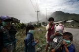 Sejumlah anak kecil mengenakan masker saat gunung Sinabung meletus di Kabupaten Karo, Sumut, Minggu (15/9). Letusan yang disertai suara gemuruh dan mengeluarkan debu vulkanik itu menyebabkan ribuan warga di kawasan tersebut terpaksa diungsikan karena status gunung itu dinyatakan berbahaya dan masuk kategori Siaga (level III). ANTARA FOTO/Septianda Perdana/ss/pd/13

