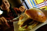 Surabaya (Antara Jatim) - Seorang perempuan mencoba sajian khas Giant Burger di The MAJ Heritage Pub & Dine, Hotel Majapahit Surabaya, Senin (16/9). Giant Burger dengan diameter 15 Cm dan dijual dengan harga Rp250 ribu/porsi tersebut, merupakan sajian khas makan siang di hotel yang dulu bernama Hotel Yamato atau Oranje. FOTO Eric Ireng/13