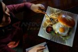 Surabaya (Antara Jatim) - Seorang perempuan mencoba sajian khas Giant Burger di The MAJ Heritage Pub & Dine, Hotel Majapahit Surabaya, Senin (16/9). Giant Burger dengan diameter 15 Cm dan dijual dengan harga Rp250 ribu/porsi tersebut, merupakan sajian khas makan siang di hotel yang dulu bernama Hotel Yamato atau Oranje. FOTO Eric Ireng/13