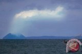 Sebuah perahu melintas saat Gunung Anak Krakatau menyemburkan asap putih di Selat Sunda, Banten, Jumat (29/11). Pos Pengamatan Gunung Anak Krakatau di Pasauran, Serang, mencatat gunung berapi itu mengalami kegempaan sebanyak 30 kali dari pagi hingga siang dan statusnya dinaikan menjadi waspada level II. ANTARA FOTO/Asep Fathulrahman/nym/2013.
