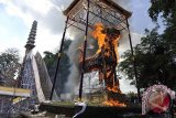 Sejumlah warga dan wisatawan menyaksikan pembakaran peti jenazah berbentuk sapi yang berisi jenazah Alm. Tjokorda Istri Sri Tjandrawati yaitu keluarga raja Puri Saren Ubud dalam upacara Ngaben di Ubud, Gianyar, Bali, Jumat (1/11). Ritual kremasi jenazah berskala besar itu dihadiri ribuan warga, wisatawan dan kerabat/keluarga raja sekaligus memberi penghormatan terakhir. ANTARA FOTO/Nyoman Budhiana/nym/2013.