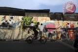 Peserta membuat grafiti di dinding tembok yang kosong sepanjang Jalan Rawa Selatan VI pada ajang Johar Baru Street Art di Johar Baru, Jakarta, Sabtu (2/11). Kompetisi grafiti yang diikuti 29 kelompok remaja tersebut dilaksanakan di tiga tempat yang rawan tawuran dengan harapan melalui kegiatan tersebut dapat meminimalisir tawuran antar kelompok remaja serta ajang untuk menyalurkan bakat bagi remaja yang senang menggambar. ANTARA FOTO/Zabur Karuru