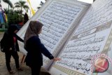 Dua orang melihat replika Al-Quran raksasa yang dipajang di Masjid Raya Al-Azhom, Tangerang, Banten, Senin (4/11). Selain untuk menyambut tahun baru Islam 1435 H, Al-Quran raksasa tersebut juga menyemarakan fetival Al-Azhom 2013. ANTARA FOTO/Lucky.R
