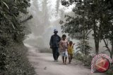 Warga melintas di pemukiman yang diselimuti debu vulkanik Gunung Sinabung di Desa Mardinding, Kabupaten Karo, Senin (4/11). Gunung Sinabung kembali erupsi pada Minggu (3/11), membuat ribuan warga Desa Mardinding mengungsi. ANTARA FOTO/Rony Muharrman/nym/2013.