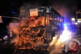 Petugas pemadam kebakaran berusaha memadamkan api yang membakar bus PO Sugeng Rahayu di Jalan Raya Perak, Jombang, Jatim, Kamis (26/12) malam. Bus bernomor plat W 700 ZO jurusan Surabaya - Yogyakarta itu dibakar massa setelah menabrak satu keluarga hingga tewas yakni Khusnul Kotimah (38), Wahyudi (16) dan seorang balita bernama Santoso (5). ANTARA FOTO/Syaiful Arif/nym/2013.