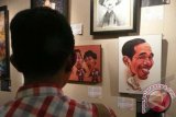 Pengunjung memperhatikan karikatur berjudul Jokowi pada pembukaan pameran Pesta Kartun Akhir Tahun di Galeri Cipta 3, TIM, Jakarta, Rabu (18/12) malam. Pameran dalam rangka HUT ke-24 Persatuan Kartunis Indonesia (PAKARTI) itu berlangsung hingga Minggu (29/12). ANTARA FOTO/Dodo Karundeng/nym/2013.