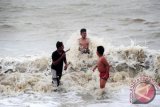 Sejumlah anak bermain air di laut Pantai Pasir Panjang, Singkawang, Kalbar, Minggu (22/12). Badan Penanggulangan Bencana Daerah (BPBD) Singkawang mengeluarkan himbauan kepada masyarakat maupun para wisawatan untuk tidak berada di pantai-pantai di Singkawang di atas pukul 13.00 wib hingga malam, menyusul ambruknya lima warung yang berada di bibir pantai akibat diterpa ombak tinggi dan angin kencang. ANTARA FOTO/Jessica Helena Wuysang/13