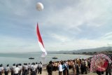 Puluhan ribu warga menyaksikan atraksi pengibaran bendara merah putih dari dasar laut Teluk Palu di Pantai Talise Palu, Sulawesi Tengah, Sabtu (14/12). Pengibaran bendera seluas 1.000 meter persegi oleh TNI AL itu merupakan bagian dari peringatan Hari Nusantara Nasional yang dipusatkan di Palu. ANTARA FOTO/Basri Marzuki/wra/13.