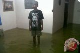 Seorang anak dari Desa Sidas, Kecamatan Sengah Temila, Kabupaten Landak, berada di dalam rumahnya yang sedang dilanda banjir. Air sungai Sidas meluap hingga naik ke permukaan hingga merendam sejumlah jalan dan rumah penduduk akibat diguyur hujan sejak Selasa tengah malam (3/12).  (Foto Tim/Kundori)