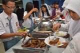 Madiun (Antara Jatim) - Sejumlah pelajar antre mengambil makan menggunakan lauk ikan saat digelar Sosialisasi Gerakan Makan Ikan (Gemarikan) di Asrama Haji Kota Madiun, Selasa (17/12). Kegiatan tersebut untuk mendorong masyarakat agar meningkatkan konsumsi ikan, karena tingkat konsumsi ikan di Kota Madiun tergolong rendah yaitu 13 kg/orang/tahun, jauh di bawah tingkat konsumsi ikan nasional 26 kg/orang/tahun. FOTO Siswowidodo/13/Chan.