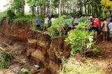 Tulungagung (Antara Jatim) - Sejumlah warga di Desa Sukowiyono, Kecamatan Karangrejo, Tulungagung, Selasa (17/12) bersiap membongkar pekuburan desanya karena rawan longsor.  Sedikitnya 13 makam dibongkar dan jasadnya dipindahkan ke area aman. Meningkatnya debit air sungai pengendali banjir di desa tersebut menyebabkan sejumlah tangkis dan plengseng sungai hancur dan menggerus area pemukiman penduduk setempat, termasuk pekuburan desa. Foto Destyan Sujarwoko/13/Oka.