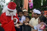 Seorang umat Katolik yang berperan sebagai Sinterklas, membagikan hadiah kepada sejumlah anak seusai pagelaran tari pada perayaan Hari Natal di Gereja Katolik Hati Kudus Yesus Palasari, Jembrana, Bali, Rabu (25/12). Umat Katolik di desa wisata tersebut telah mewarisi tradisi pentas kesenian, iringan gamelan Bali serta berpakaian adat Bali saat mereka ke Gereja. ANTARA FOTO/Wira Suryantala/wra/13.