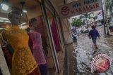 Seorang warga melintas di depan sebuah toko tekstil saat genangan masih merendam di Kawasan Pasar Baru, Jakarta, Rabu (22/1). Sejumlah wilayah di Ibu Kota kembali terendam banjir akibat meluapnya sejumlah sungai. ANTARA FOTO/Zabur Karuru/wra/14