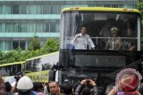 Gubernur DKI Jakarta Joko Widodo (kiri) mencoba bus tingkat pariwisata pada peresmian bus tersebut di Bundaran HI, Jakarta, Kamis (16/1). Bus pariwisata asal Cina tersebut memiliki 62 kursi yang terdiri dari 20 kursi di bawah dan 40 kursi di atas serta dua kursi untuk penyandang disabilitas, rencananya akan beroperasi melayani wisatawan secara gratis pada awal Februari. ANTARA FOTO/Zabur Karuru