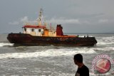 Seorang warga melihat kapal penarik (tugboat) yang terseret gelombang di Pantai Tana Beru, Bulukumba, Sulsel, Kamis (16/1). Kapal tersebut terseret arus gelombang hingga ke bibir pantai. Syahbandar Bulukumba mengeluarkan imbauan kepada nelayan untuk waspada melaut karena gelombang laut di perairan Bulukumba dan sekitarnya dalam sepekan terakhir mencapai 5 meter. ANTARA FOTO/Ekho Ardiyanto/wra/14