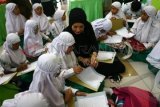 Mantan peragawati Arzeti Bilbina (tengah) mendampingi pelajar SD-SMA Khadijah Surabaya menyelesaikan penulisan ayat Al-Quran disela-sela pameran pendidikan 