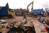 Sebuah alat berat menurunkan sampah dari truk pengakut sampah untuk korban banjir di Tempat Pembuangan Akhir (TPA) Sumompo, Manado, Sulawesi Utara, Kamis (23/1). Pemerintah kota Manado memperkirakan sampah pasca banjir yang dihasilkan bisa mencapai 50 ribu kubik per hari. ANTARA FOTO/Fiqman Sunandar/wra/14.