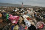 Sejumlah warga berada di antara sampah yang menumpuk di pantai Karangsong, Indramayu, Jawa Barat, Minggu (26/1). Pascabanjir yang melanda sebagian wilayah di Pantura Indramayu, sampah-sampah dari kota yang mengalir ke laut yang terbawa banjir dihempaskan ombak ke pantai sehingga bertumpuk dan menimbulkan bau busuk. ANTARA FOTO/Dedhez Anggara/wra/14.