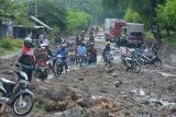 Situbondo (Antara Jatim) - Sejumlah pengendara sepeda motor melintasi material banjir di jalan raya Pantura Dusun Pecaron, Desa Klatakan Kecamatan Kendit, Situbondo, Jawa Timur, Sabtu (1/2). Jalan raya pantura Situbondo yang menghubungkan Surabaya - Banyuwangi lumpuh total mencapai puluhan kilometer akibat material banjir berupa lumpur, pasir, dan batu.  
ANTARA FOTO/Seno/14/SHP.