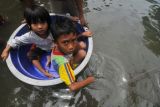 Dua anak berada dalam tempat penampungan menerobos banjir yang melanda sebuah permukiman di Penjaringan, Jakarta Utara, Rabu (22/1). Luapan sejumlah kali yang melintas Ibu Kota sejak Selasa (21/1) malam hingga Rabu (22/1) dinihari telah mengakibatkan sejumlah permukiman dan jalan utama di Jakarta kembali terendam. ANTARA FOTO/Zabur Karuru/mes/14