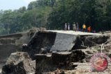 Sejumlah warga melintas di atas tanggul yang amblas di kali Siman, Desa Siman, Kediri, Jawa Timur, Rabu (26/2). Luapan aliran lahar hujan Gunung Kelud pada selasa malam membuat bangunan tanggul amblas dan mengancam pemukiman rumah warga di kawasan pingiran kali Siman. ANTARA FOTO/Rudi Mulya/wra/14