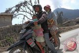 Seorang pria bersama isteri dan anaknya warga kaki Gunung Sinabung membawa hewan peliharaan mereka ketika akan kembali ke lokasi pengungsian, di Desa Sigarang-garang, Karo, Sumut, Kamis (6/2). Pasca erupsi besar disertai awan panas, Sabtu (1/2) yang mengakibatkan 16 orang meninggal dunia, sebagian warga mulai mengungsikan hewan peliharaan mereka untuk menghindari terkena dampak awan panas dan juga pencurian. ANTARA FOTO/Irsan Mulyadi/nym/2014.