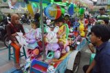 Madiun (Antara Jatim) - Sejumlah anak naik di atas odong-odong yang dilengkapi lampu kelap-kelip dan diiringi lagu anak-anak di sekitar Alun-alun Madiun, Minggu (2/2). Pemilik odong-odong yang digerakkan dengan accu tersebut menarik ongkos Rp1.000 peranak perlagu. (FOTO Siswowidodo/14/edy)