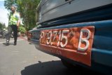 Bondowoso (Antara Jatim) - Anggota polisi lalu lintas berjalan didekat kendaraan dinas plat merah yang parkir di Jalan Ahmad Yani, Bondowoso, Jawa Timur, Minggu (20/4). Menurut data samsat Bondowoso, mulai 2009 sebanyak 33.000 kendaraan roda dua dan roda empat kendaraan dinas pemerintah Bondowoso menunggak membayar pajak.FOTO Seno/14/Chan.