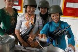 Sejumlah anggota Jalasenastri (istri prajurit Korps Marinir TNI AL) dari Batalyon Intai Amfibi-1 (Taifib-1) Marinir, menggelar demo memasak dengan berkebaya dan mengenakan helm tempur serta memanggul senapan serbu, di BatalyonbTaifib-1 Marinir, Bhumi Marinir Karangpilang Surabaya, Senin (21/4). Kegiatan tersebut bertujuan untuk memperingati Hati Kartini, dalam nuansa khas prajurit Korps Marinir. ANTARA FOTO/Eric Ireng/ed/pd/14