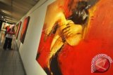 Pengunjung mengamati lukisan pada pameran tunggal karya Hudi Alfa yang bertajuk Women In Red di TIM, Jakarta, Sabtu (19/4). Pameran yang mengesplorasi tubuh dan gesture dalam berbagai pose tersebut berlangsung hingga 27 April 2014. ANTARA FOTO/Zabur Karuru