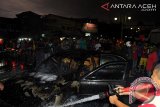 Petugas pemadam berusaha memadamkan api yang membakar mobil sedan Nisan dengan Nomor polisi BL 357 PQ di jalan Teuku Nyak Arif, Jambu Tape, Banda Aceh, Jumat (9/5). Empat penumpang terdiri suami istri dan duanak  berhasil keluar dari mobil saat terbakar itu atas bantuan warga di sekitar lokasi, diduga penyebab terbakar mobil itu akibat korseleting kabel.ANTARAACEH.COM/Ampelsa/14.