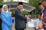 Martapura, 3/5 - Bupati Banjar Sultan H Khairul Saleh didampingi Ketua Penggerak PKK Kabupaten Banjar Hj. Raudhatul Jannah Khairul Saleh menyerahkan piagam penghargaan dan piala dari Presiden RI kepada Rizky Aditya, siswa SDN Tunggul Irang Ulu yang berhasil menyabet Juara 1 Lomba Karate Tingkat Nasional dalam rangkaian Peringatan Hari Pendidikan Nasional 2014 dengan tema "Pendidikan Untuk Peradaban Indonesia yang Unggul" di Martapura, Jumat (2/5).(Foto Antara/humas/E)