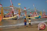 Dua anak nelayan, menyaksikan perahu hias, di Pantai Jumiang, Pademawu, Pamekasan, Jatim, Rabu (7/5).Perahu hias yang dipersiapkan untuk upacara petik laut pada tanggal 7-9 Mei itu, sebagai ungkapan syukur atas keselamatan dan melimpahnya ikan tangakapan dalam satu tahun terakhir, sekaligus sebagai ajang pelestarian budaya warisan leluhur. ANTARA FOTO/Saiful Bahri/wdy/14.