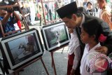 Wakil Gubernur Kalsel Rudy Resnawan dan dua siswa SD menyaksikan foto karya pelajar yang menjadi juara Lomba Foto Pendidikan 2014 tingkat Pelajar se Kalsel di ajang peringatan Hardiknas 2014 di halaman kantor Gubernur Kalsel, Jumat (2/5). Lomba Foto Pendidikan 2014 tingkat Pelajat se Kalsel di gelar Komunitas Jurnalis Pena Hijau dan Disdik Kalsel. Foto Antaranews Kalsel/Herry Murdy Hermawan