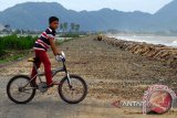 Anak-anak bermain sepeda di jalan pantai wisata yang tertinbun pasir dan kerikil di Desa Kampung Jawa, Banda Aceh, Jumat (13/6). Jalan pantai wisata itu tertimbun pasir dan kerikll akibat diterjang gelombang besar yang terjadi sejak  tiga hari terakhir, meskipun di lokasi tersebut sudah dibangun tranggul.<br />
ANTARAACEH.COM/Ampelsa/14