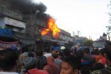 :  Masyarakat menyaksikan petugas pemadam kebakaran  memadamkan kobaran api yang menghanguskan bangunan pertokoan di kawasan Pasar Tradisional Pematang Siantar, Sabtu (21/6).  Api juga menghanguskan ratusan kios di pasar tradisional tersebut.  (Foto Antarasumut/Waristo)