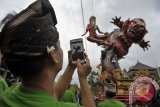 Seorang pemuda menggunakan fitur kamera pada telepon genggam untuk mengabadikan "Ogoh-Ogoh" hasil karya kelompoknya dalam Festival Ogoh-Ogoh 2014 menjelang Hari Raya Nyepi Tahun Saka 1936 di Desa Tegallalang, Gianyar, Bali, Sabtu (29/3). mat Hindu menggelar parade Ogoh-Ogoh berkeliling kampung untuk menetralisir kekuatan negatif dan sifat buruk agar Hari Raya Nyepi dapat dilaksanakan dengan penuh keheningan serta tanpa gangguan apapun. ANTARA FOTO/Nyoman Budhiana/2014.