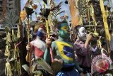 Sejumlah anak dengan riasan tubuh warna-warni dan bendera peserta Piala Dunia 2014, berjalan berkeliling kampung membawa peralatan upacara dalam ritual Grebeg di Desa Tegallalang, Gianyar, Bali, Rabu (25/6). Tradisi ritual berkeliling kampung dengan riasan tubuh warna-warni sebagai cerminan mahluk menyeramkan itu dipercaya sebagai penolak bala dan untuk menciptakan keharmonisan. ANTARA FOTO/Nyoman Budhiana/nym/2014.