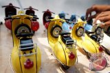 Seorang perajin menata kerajinan miniatur Vespa setelah proses pengecatan, di industri rumahan, Desa Kepulungan, Gempol, Pasuruan, Jatim, Kamis (10/7). Kerajinan tangan tersebut dijual dengan harga Rp 120 ribu - Rp 200 ribu. ANTARA FOTO/Adhitya Hendra/ss/pd/14.