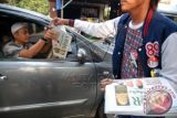 Seorang simpatisan pendukung capres Joko Widodo membagikan tabloid Rahmatan Lil'Alamin kepada warga di Jalan Jatimulya, Depok, Jabar, Jum'at (4/7). Para simpatisan membagikan tabloid Lentera Indonesia, tabloid Kopi Pagi (kotak-kotak putih penyelamat negeri), dan tabloid Rahmatan Lil'Alamin untuk menghadang kampaye hitam melalui peredaran koran Obor Rakyat yang memfitnah pasangan capres nomor urut dua Jokowi-JK di sejumlah daerah. ANTARA FOTO/Indrianto Eko Suwarso/wdy/14