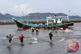 Nelayan mengevakuasi barang-barang  kebutuhan melaut saat kapal mereka kandas diterjang badai dan ombak besar di muara Sungai Kuala Lampulo, Banda Aceh, Selasa (16/9). Kapal nelayan itu diterjang angin kencang dan ombak besar saat memasuki muara pelabuhan , sedangkan belasan nelayan berhasil selamat berenang ke tepian. ANTARAACEH.COM/Ampelsa/14